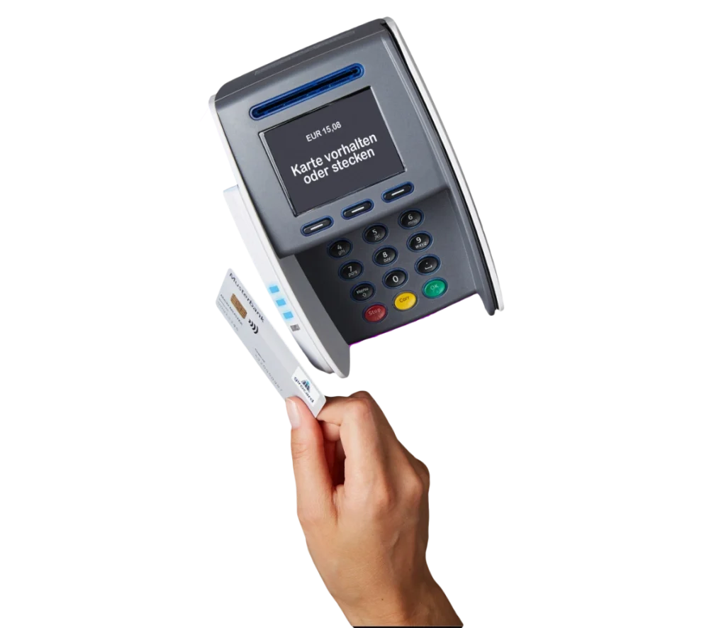 Hand, die eine Kreditkarte hält, vor einem modernen Kartenlesegerät, das zur Bezahlung verwendet wird, mit der Aufforderung, die Karte vorzulegen oder einzustecken.